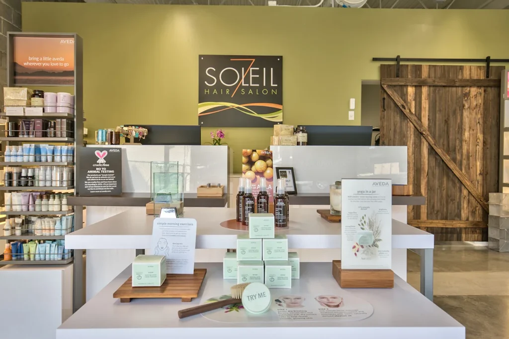 Interior of a modern hair salon with product displays on a counter, a "Soleil Hair Salon" sign on the wall, and shelves stocked with hair and skincare products. - Soleil 7 Hair Salon in Tallahassee, FL